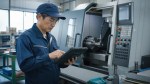 町工場で作業記録とタブレットを確認する製造担当者